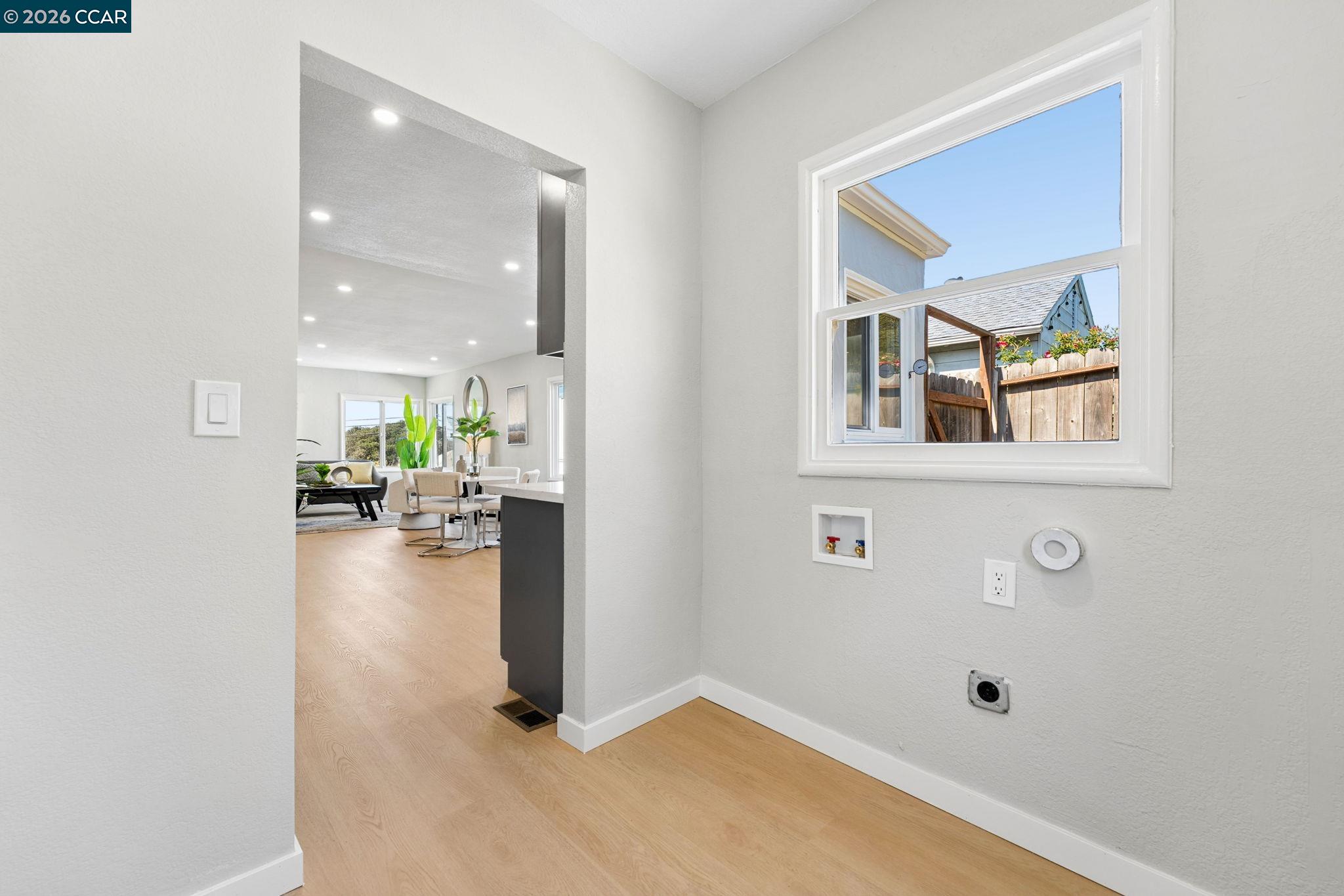 Laundry area with washer hookups and a window overlooking the fenced yard, opening onto the dining and living area.