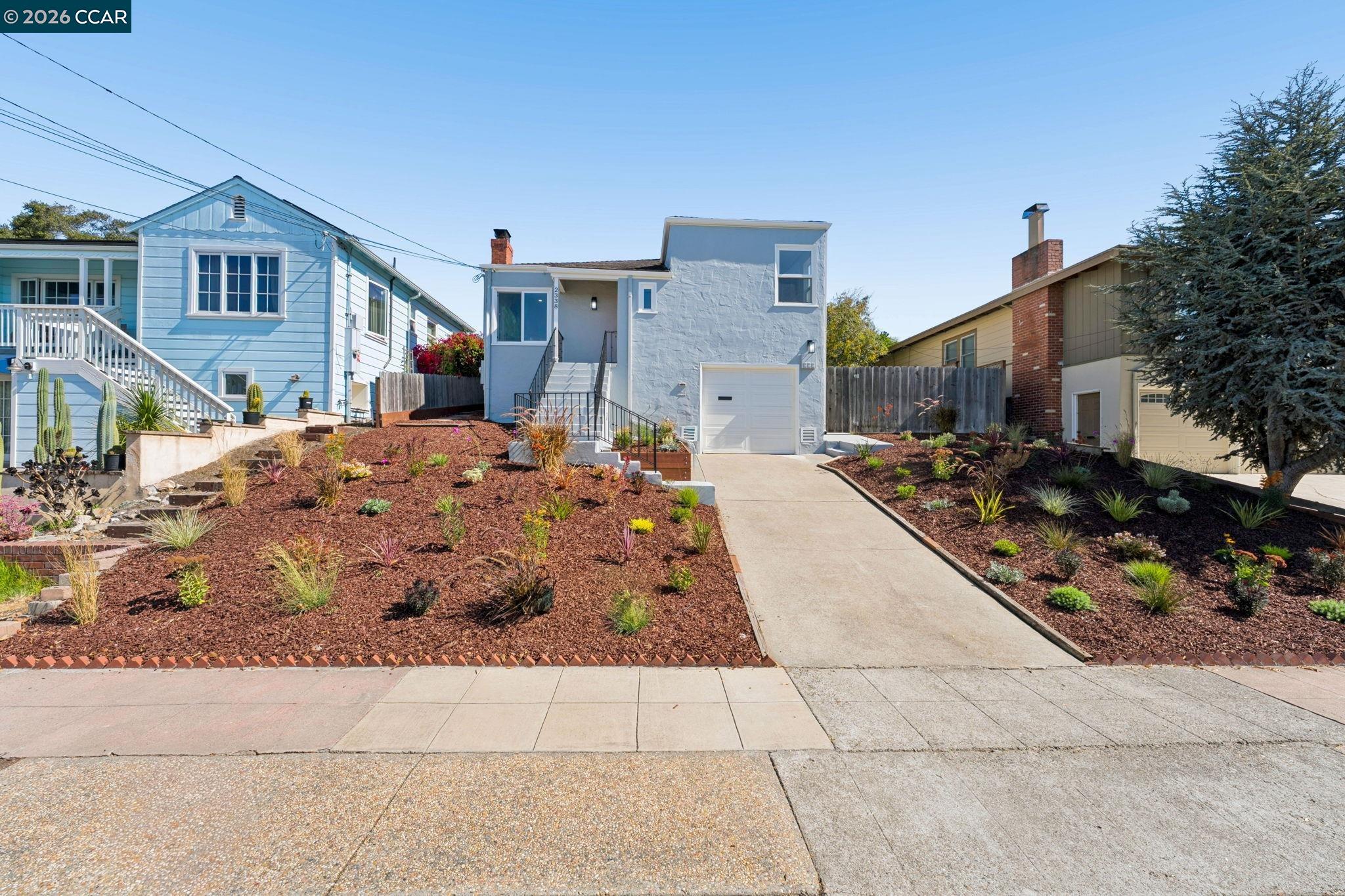 White stucco home with front steps, garage, and drought-tolerant landscaping.