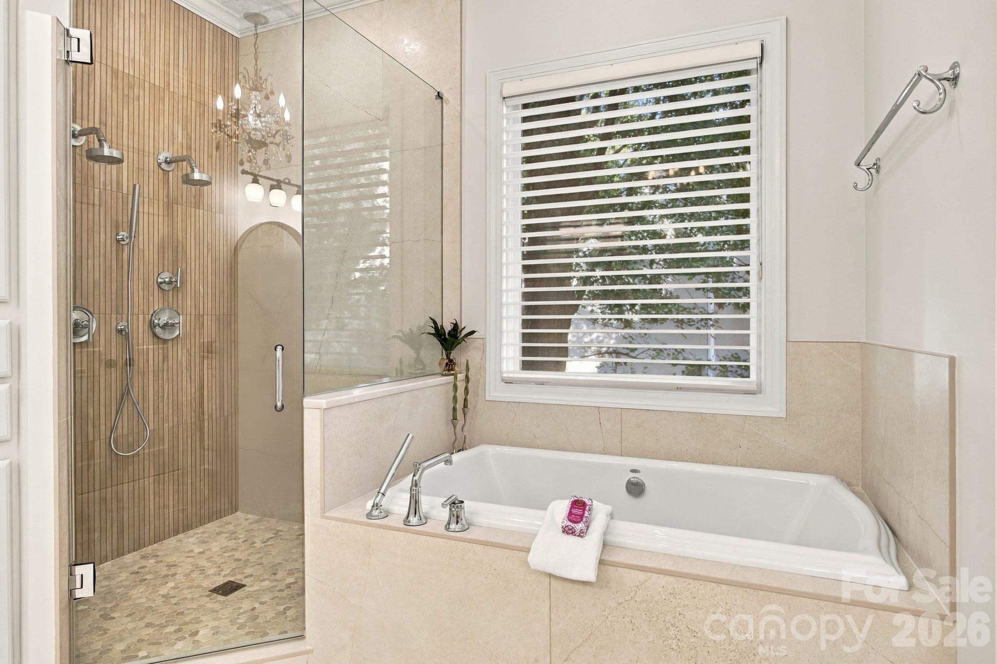 Bathroom with a glass walk-in shower and soaking tub beneath a shuttered window.