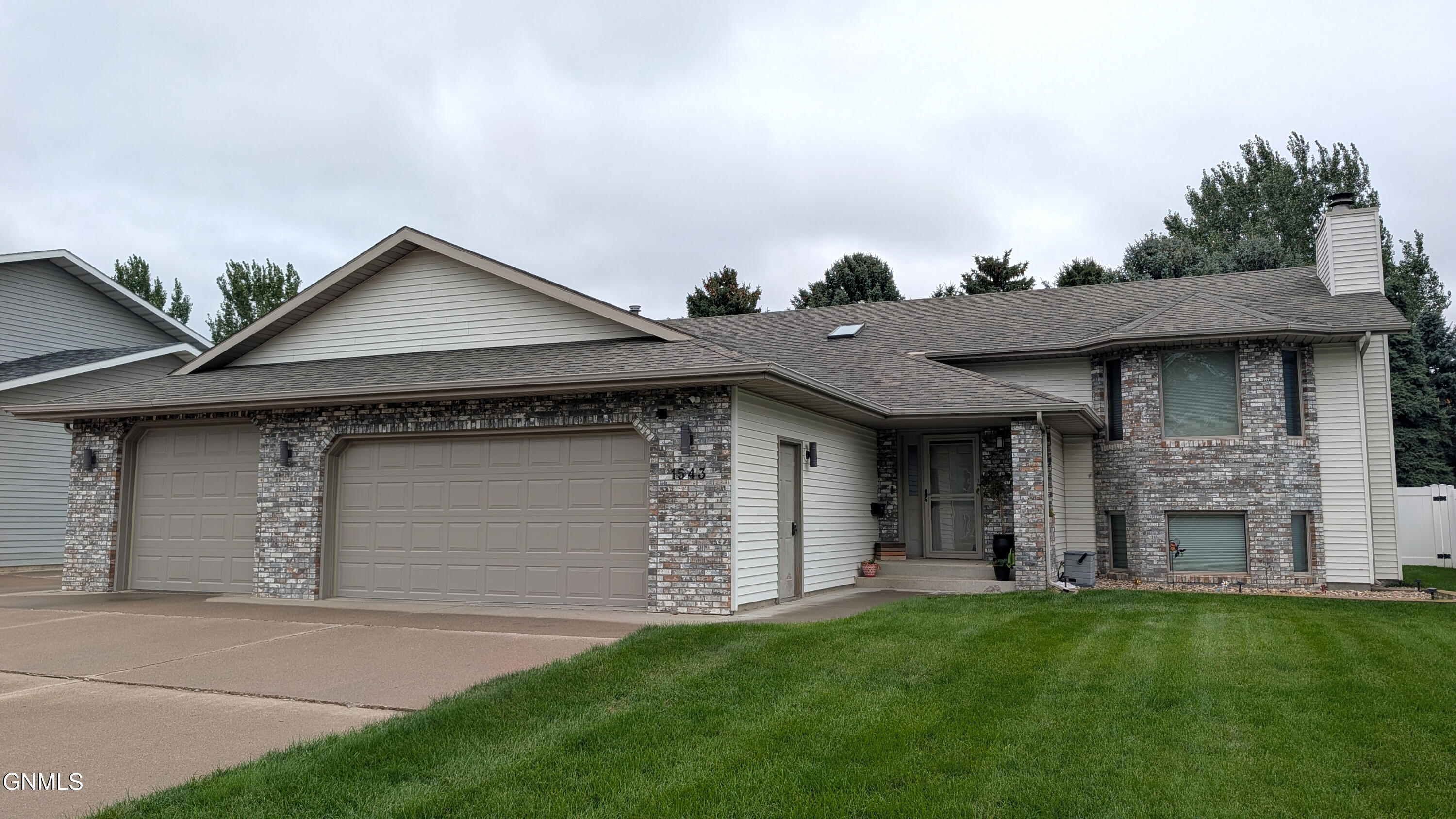 House at 1543 with a brick facade, attached two-car garage, and green front lawn.