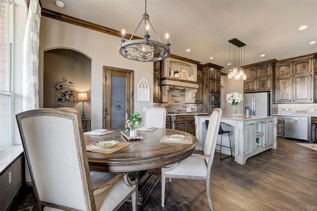 Kitchen and dining area with rustic wood cabinetry, a large island, and a round table beneath a chandelier.