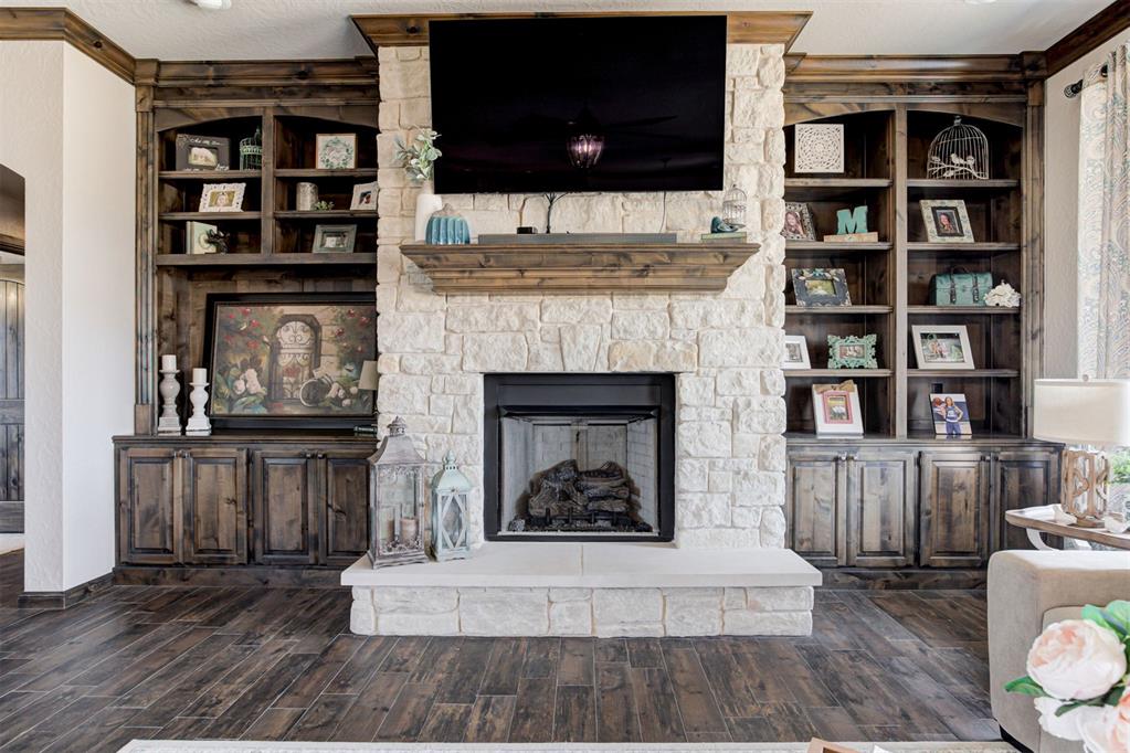 Living room with a white stone fireplace and dark wood built-in shelving.