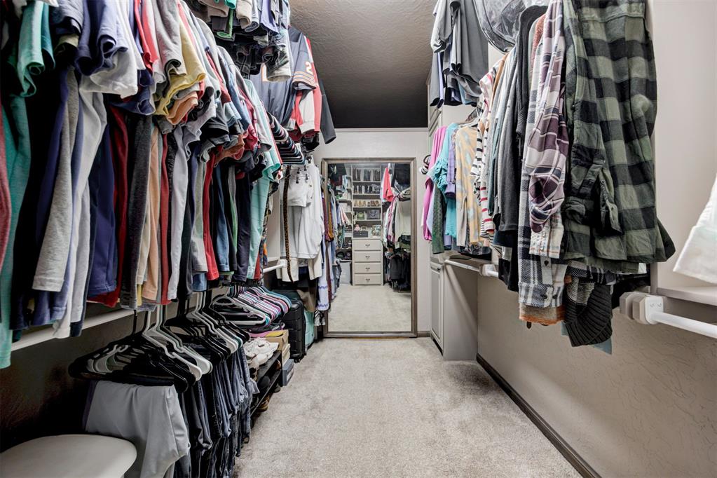Walk-in closet with clothing racks on both sides and a full-length mirror at the far end.