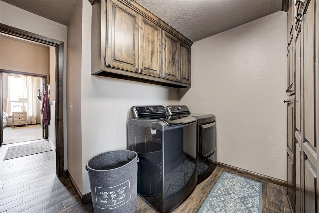 Laundry room with washer and dryer, dark wood cabinets, and a fabric hamper.