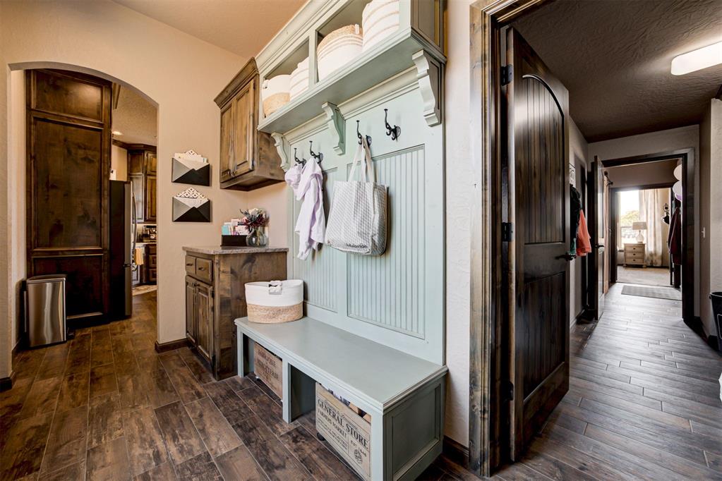 Mudroom with a pale blue built-in bench and coat hooks beside a dark-floored hallway.