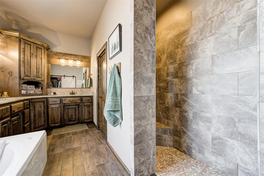 Bathroom with dark wood vanity and a spacious gray-tiled walk-in shower.