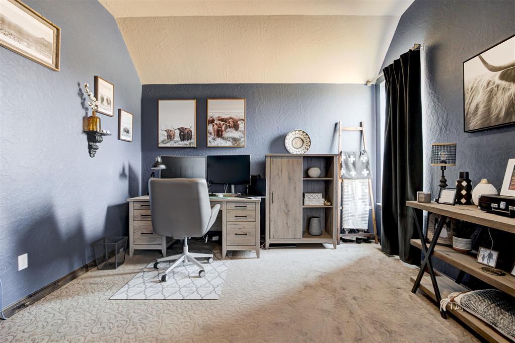 Furnished home office with blue-gray walls, a desk and computer, and western cattle artwork.
