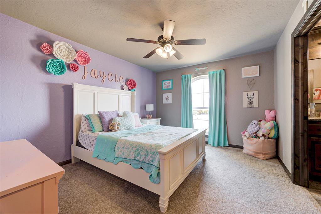 Child’s bedroom with a white bed, lavender flower-decorated wall, turquoise curtains, and stuffed animals.