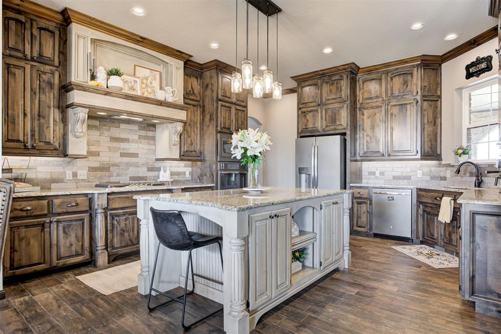 Kitchen with a stone-topped island, dark wood cabinets, and stainless steel appliances.
