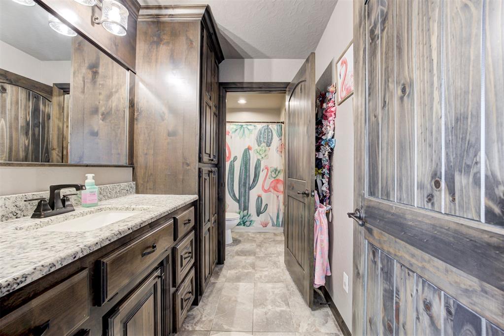 Bathroom with dark wood vanity, speckled stone countertop, and cactus-and-flamingo shower curtain.