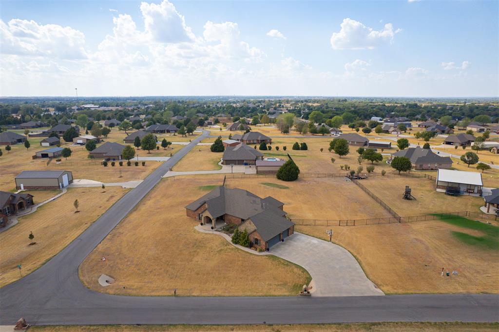 Aerial view of a brick home on a large corner lot with a curved driveway.