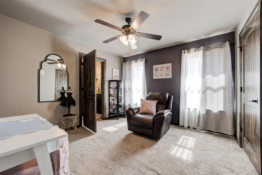Furnished room with a leather recliner, dark accent wall, ceiling fan, and sheer curtains.