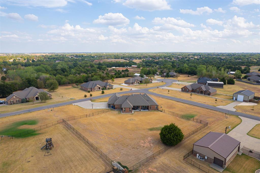 Aerial view of a brick home with a fenced backyard, playset, and detached outbuilding.