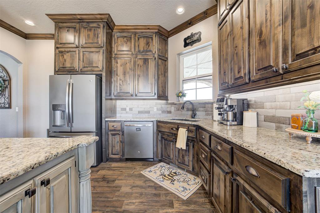 Kitchen with distressed-wood cabinets, granite countertops, stainless-steel appliances, and a window above the sink.
