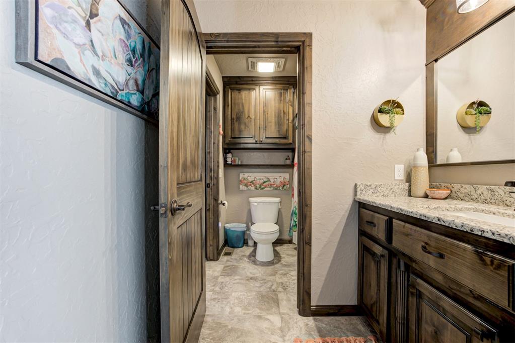 Bathroom with a wood vanity and granite counter, looking toward a separate toilet area.