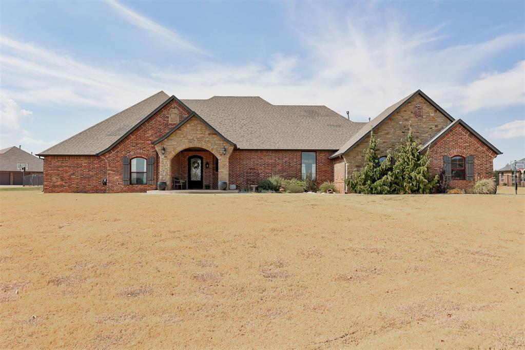 Single-story brick and stone house with a broad lawn and arched covered entry.