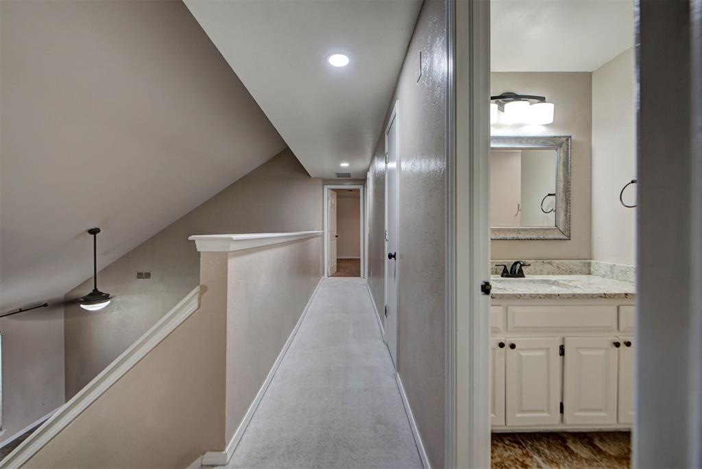 Upstairs hallway beside an open stairwell, with a bathroom vanity visible through the doorway.