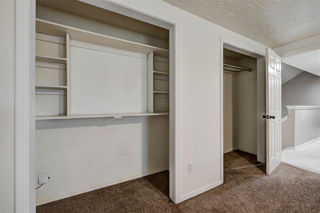 Bedroom closets with built-in shelving and a hanging rod above brown carpet.