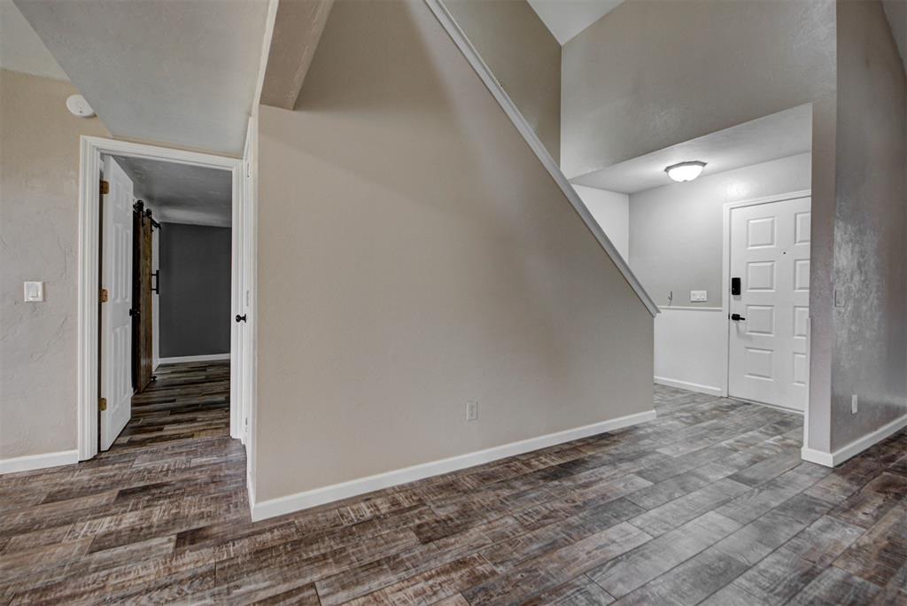 Empty entryway with wood-look tile flooring beneath a staircase