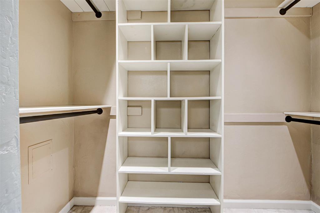 Walk-in closet with central built-in shelving and hanging rods along both sides.