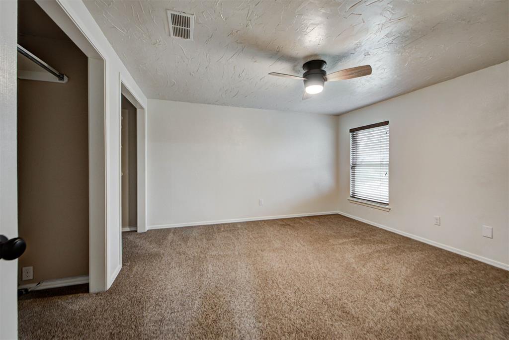 Empty bedroom with beige carpet, a ceiling fan, and an open closet beside the doorway.