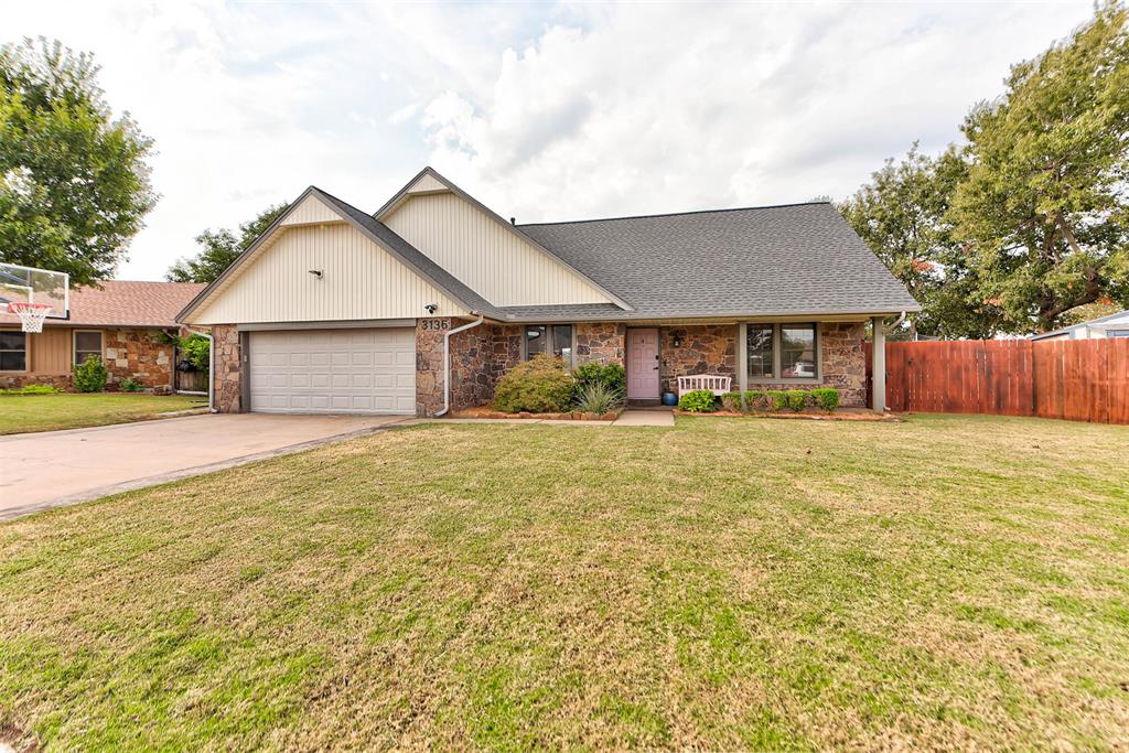 Single-story stone-and-siding home with a two-car garage and broad front lawn.