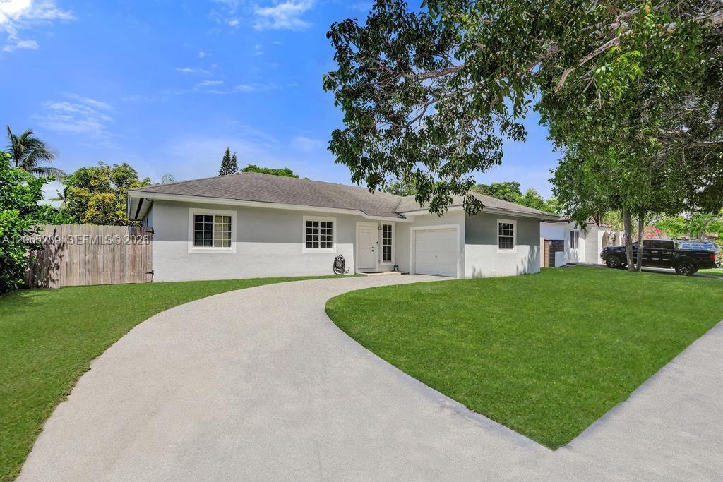 Single-story home with an attached garage, curved driveway, and broad green lawn.