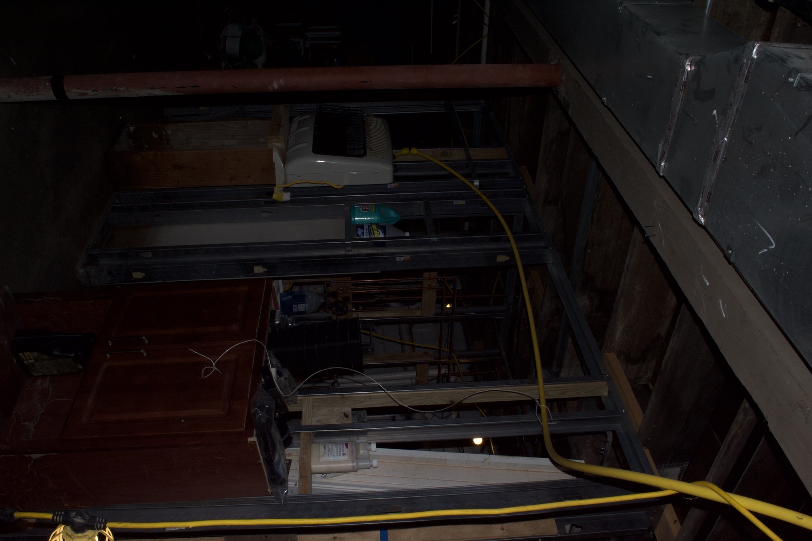 Unfinished interior with exposed framing, wiring, and building materials.