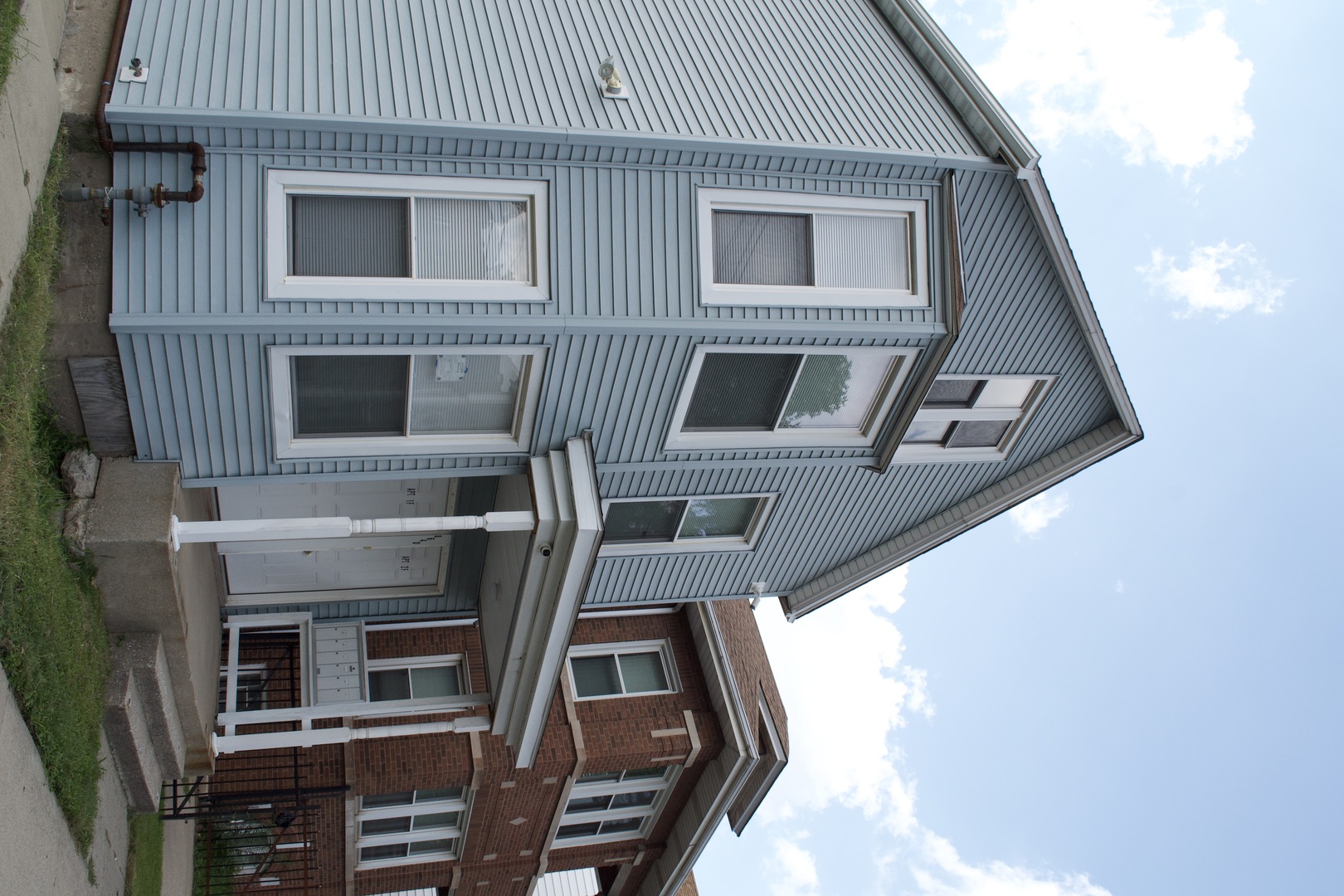 Two-story home with blue-gray siding, white-trimmed windows, and a small covered front porch.