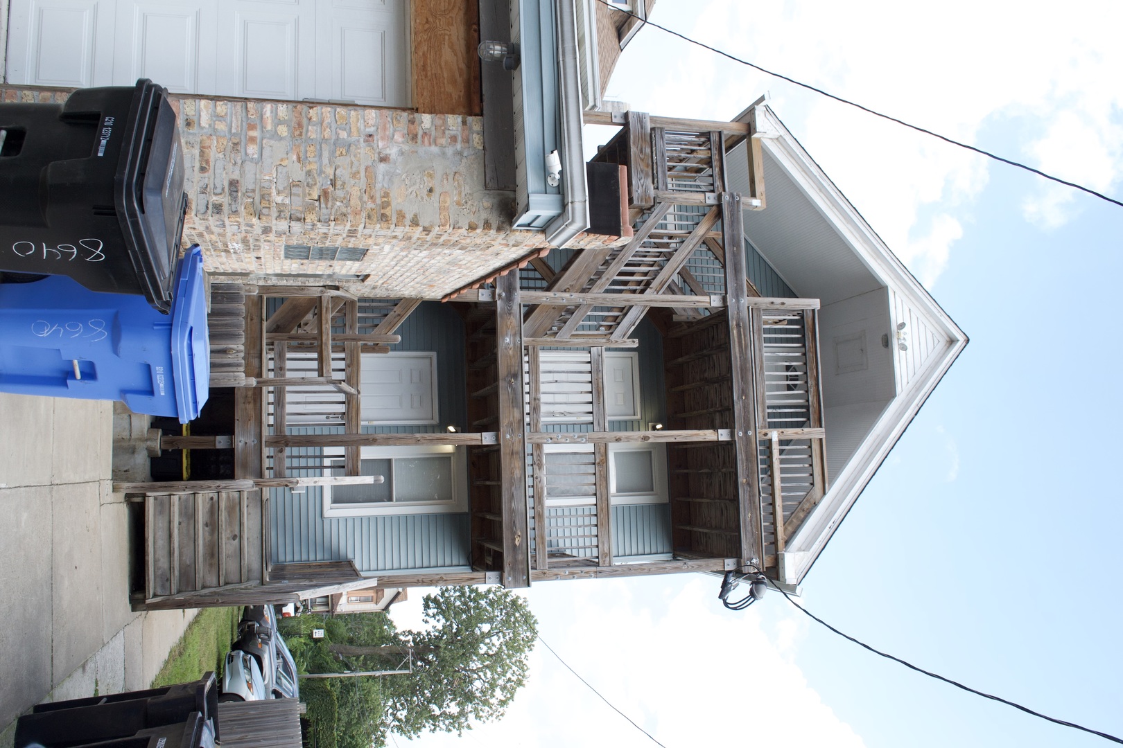 Blue-sided home with a large, multi-level wooden porch and balconies.