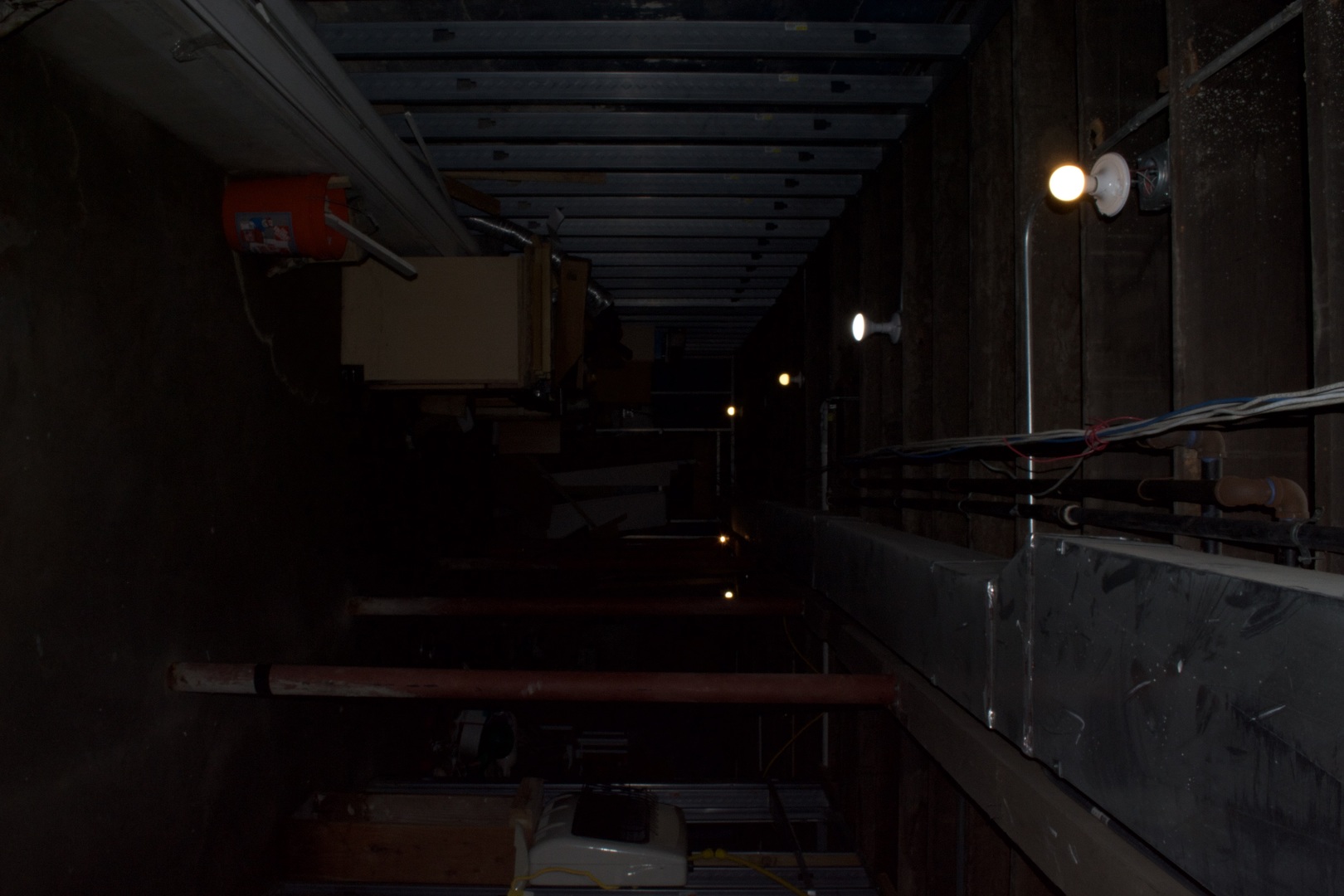 Unfinished basement utility area with exposed joists, pipes, ductwork, and wiring.