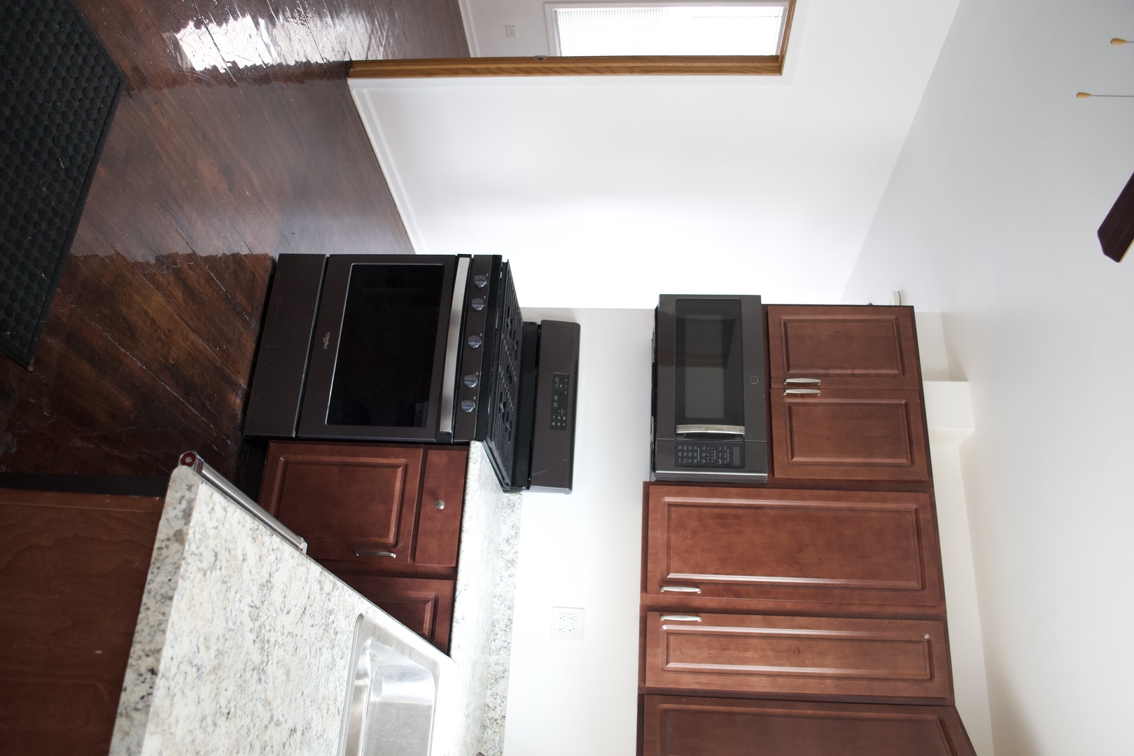 Kitchen with reddish-brown cabinets, black appliances, and granite countertops.
