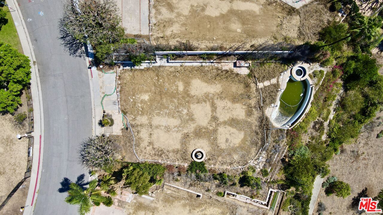 Cleared property lot with an oval pool beside a residential street.
