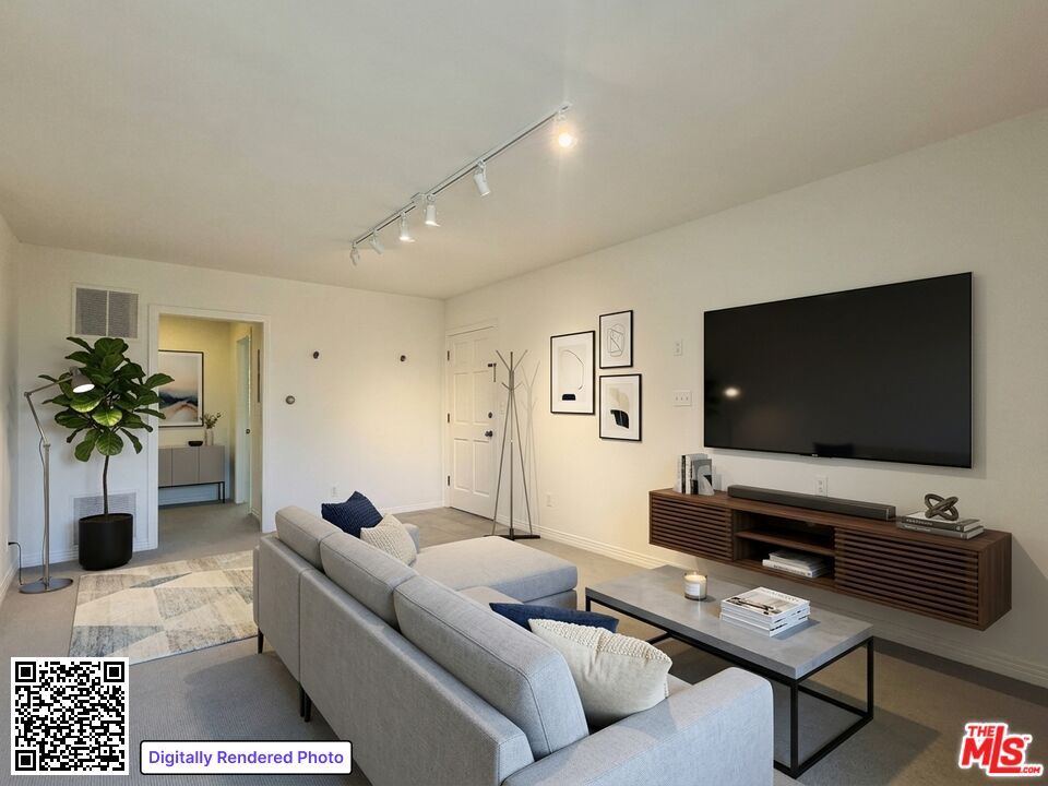 Living room with a gray sectional, geometric rug, and large television above a wooden media console.