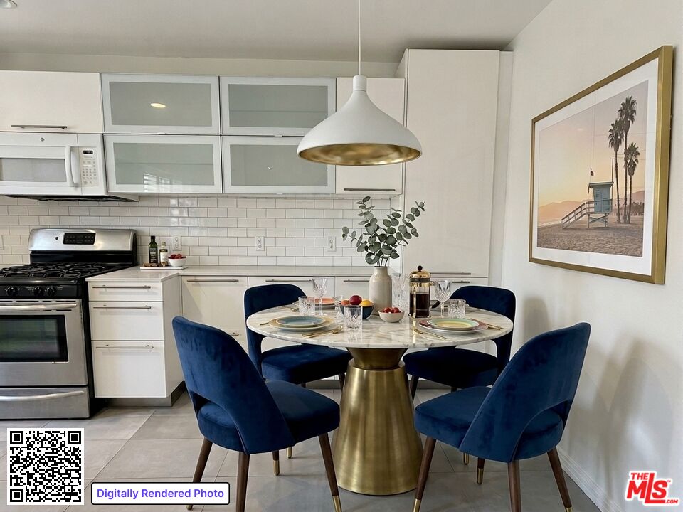 Kitchen and dining area with white cabinetry, a round table, and blue velvet chairs.