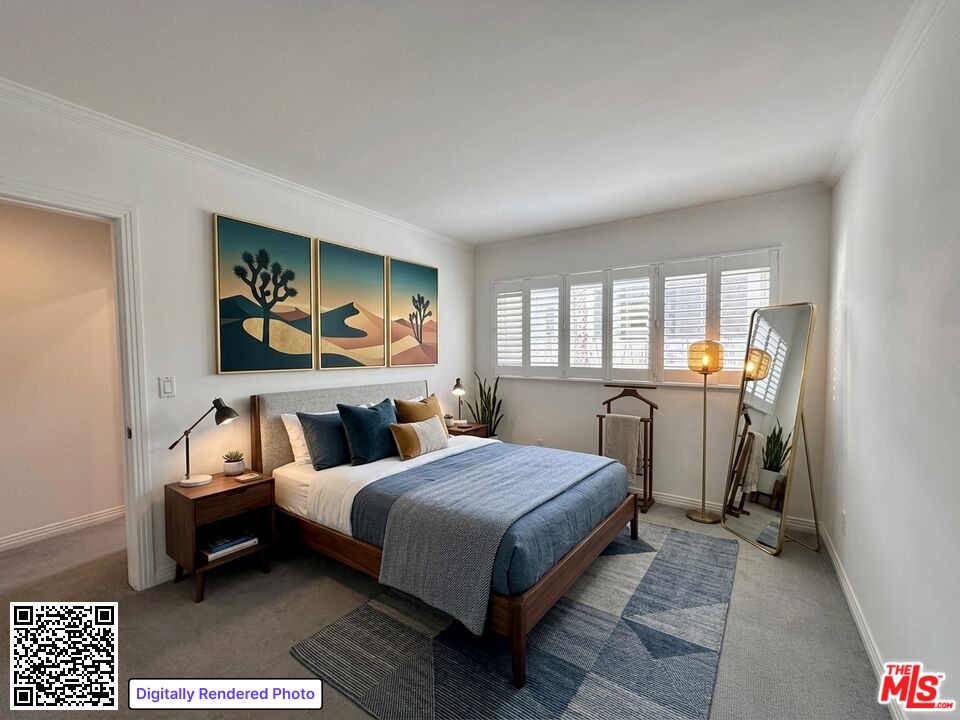 Staged bedroom with blue bedding, a geometric rug, desert artwork, and plantation shutters.