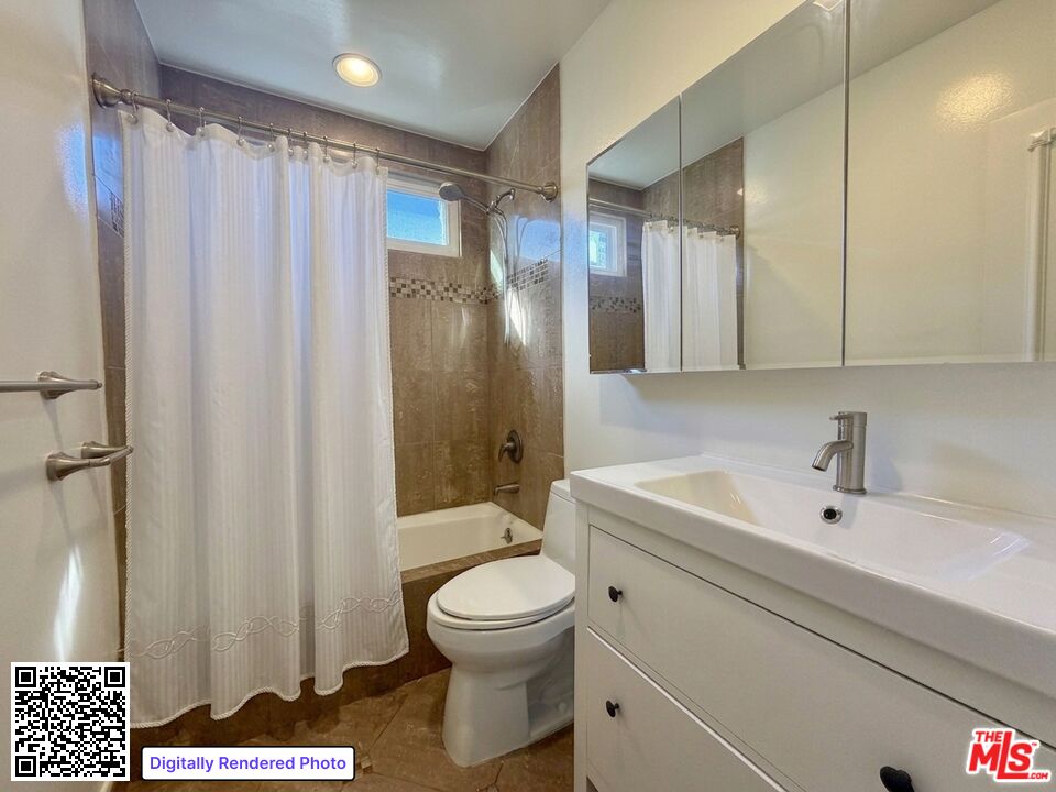Bathroom with a white vanity and mirrored cabinet beside a brown-tiled tub and shower.