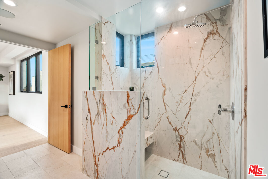 Marble walk-in shower with glass enclosure, rainfall showerhead, and a small window.