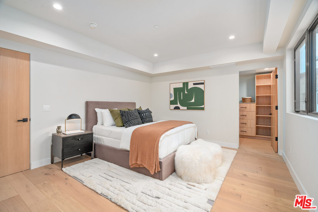 Staged bedroom with a rust-colored throw, white shag rug, and open walk-in closet.