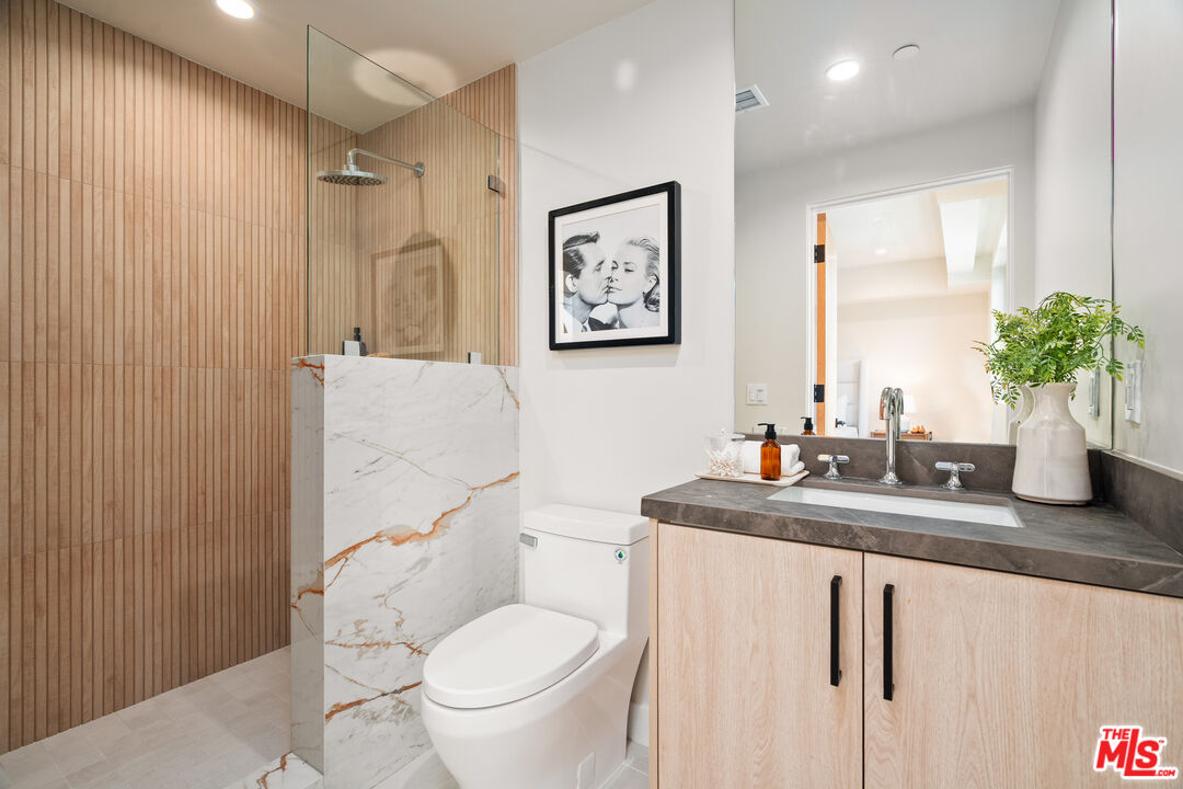 Modern bathroom with a wood-slat shower, veined marble partition, and light wood vanity.