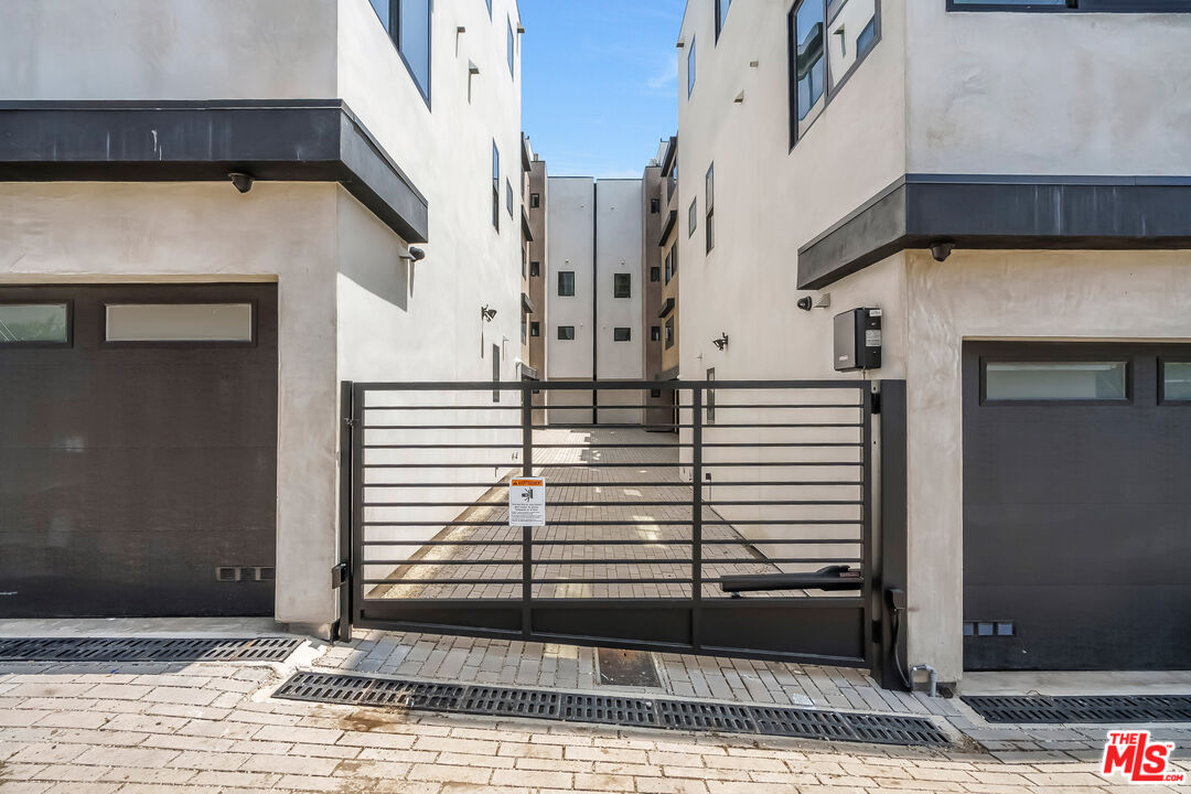Apartment building entrance behind a black metal gate, flanked by dark garage doors.