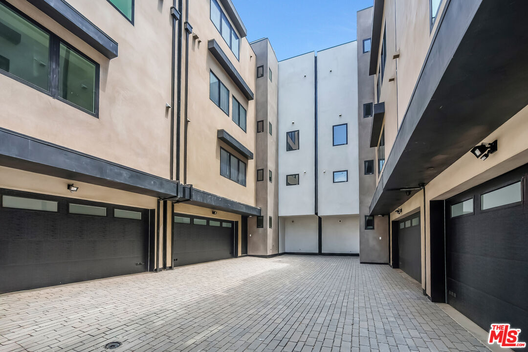 Modern residential courtyard with paved ground and multiple garage doors.