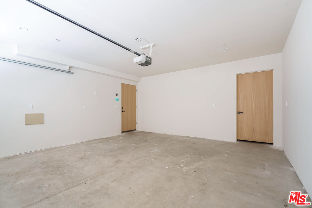 Vacant garage with a bare concrete floor, garage door track, and two wooden doors.