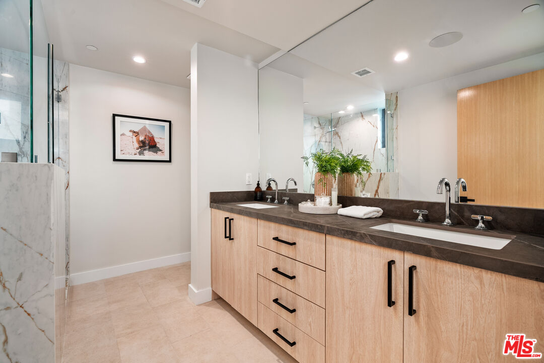 Contemporary bathroom with a double-sink light-wood vanity and marble shower walls.