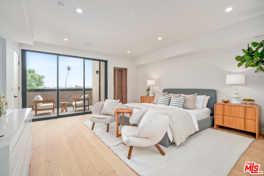 Furnished bedroom with a gray bed and sliding glass doors opening to a balcony.