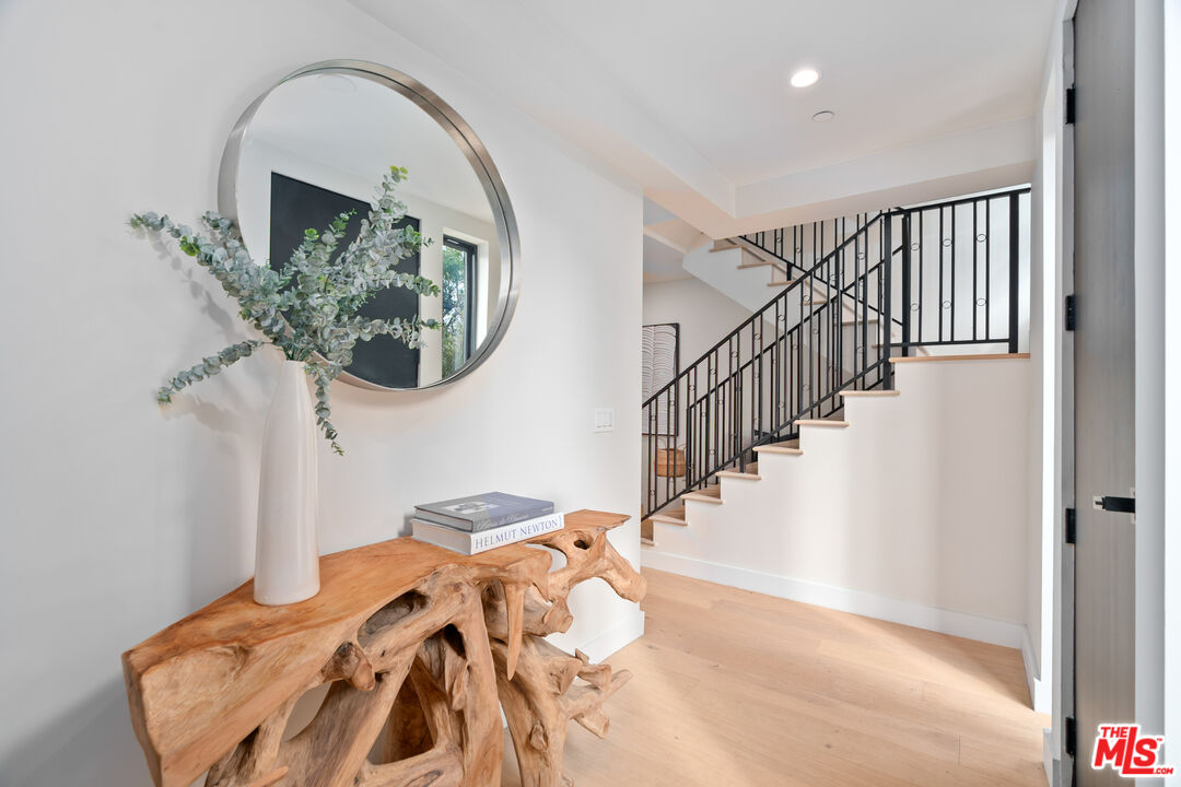 Home entryway with a sculptural wood console and black metal staircase.