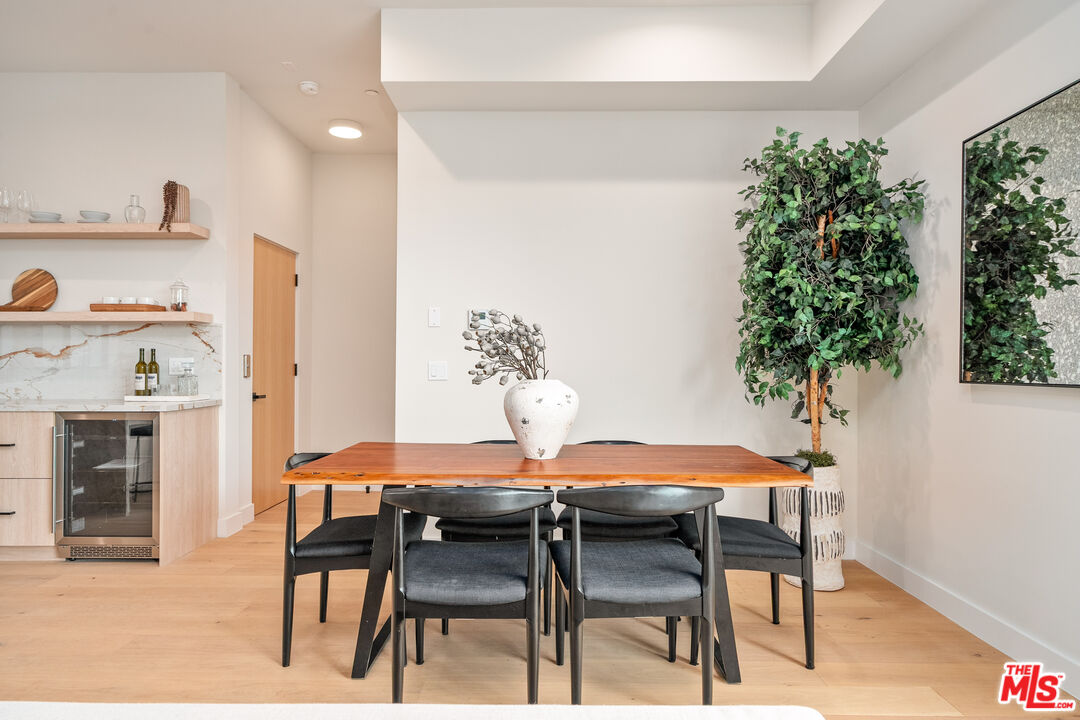 Dining room with a wood table, dark chairs, and an open kitchen with marble backsplash.