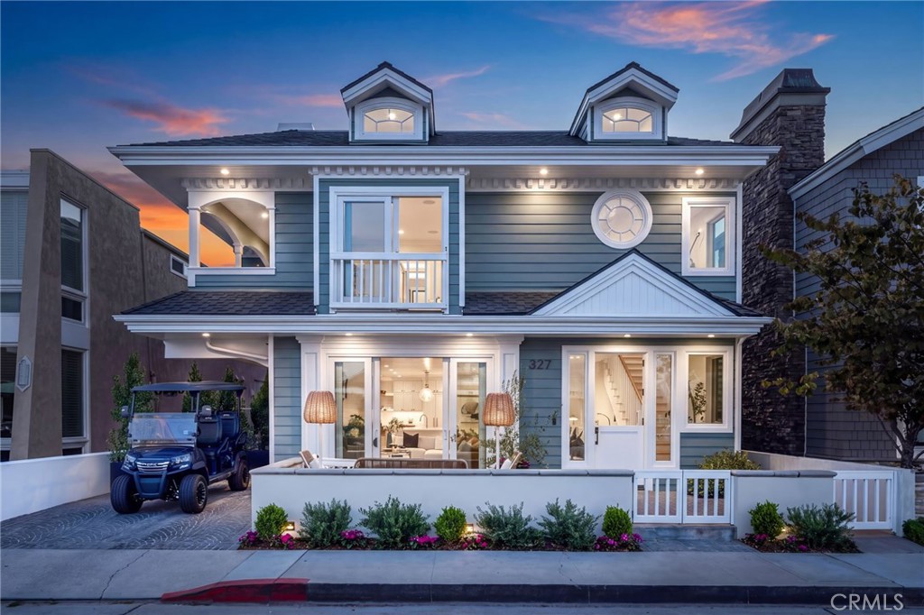 Blue two-story coastal-style home with white trim and a golf cart at dusk.