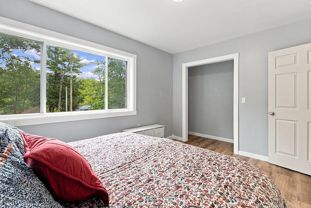Bedroom with a floral bedspread, red pillows, and a large window overlooking trees.