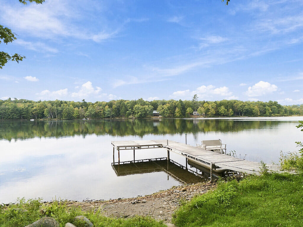 Wooden dock on a calm lake, with a wooded shoreline reflected across the water.